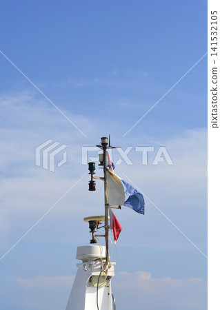 Ship mast with radar and flags against blue sky Ship mast with radar and flags against blue sky 141532105