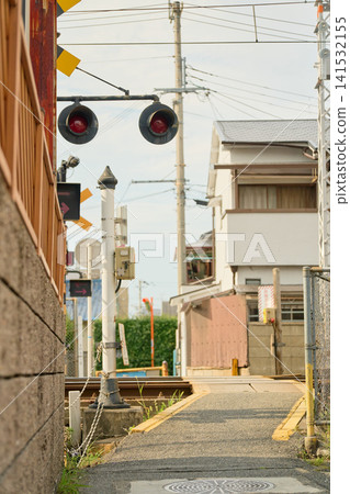 A local railway crossing sandwiched between a concrete wall and a private house. Emergency button displayed. A local railway crossing sandwiched between a concrete wall and a private house. Emergency button displayed. 141532155