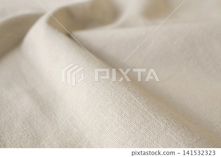 Beige linen fabric with soft folds. Beige linen fabric texture, natural organic fabric. Seasonal summer fabric. Beige linen fabric with soft folds. Beige linen fabric texture, natural organic fabric. Seasonal summer fabric. 141532323