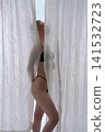 Elegant nude woman from back standing between white sheer curtains 141532723