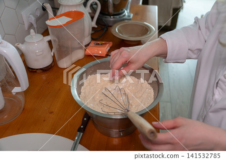 Hands mixing flour in metal bowl with whisk on wooden kitchen countertop, ingredient preparation for baking process. Baking preparation, recipe illustration, cooking education, culinary blog, food Hands mixing flour in metal bowl with whisk on wooden kitchen countertop, ingredient preparation for baking process. Baking preparation, recipe illustration, cooking education, culinary blog, food 141532785