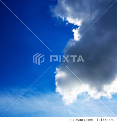 large dark rain cloud against a clear blue sky with white edges illuminated by sunlight large dark rain cloud against a clear blue sky with white edges illuminated by sunlight 141532820