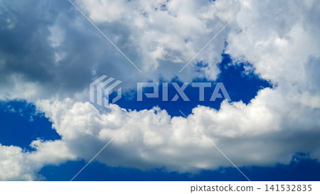 dark and white cumulus clouds with a clearance of blue sky in the center 141532835