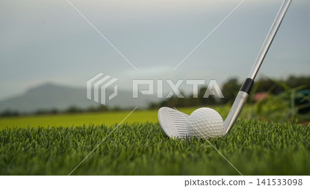 Golf clubs and balls on a green lawn in a beautiful golf course with morning sunshine. Golf clubs and balls on a green lawn in a beautiful golf course with morning sunshine. 141533098