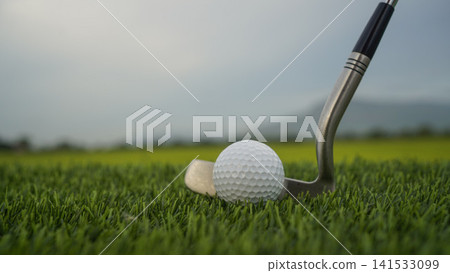 Golf clubs and balls on a green lawn in a beautiful golf course with morning sunshine. Golf clubs and balls on a green lawn in a beautiful golf course with morning sunshine. 141533099