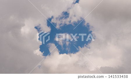 Soft white clouds surround broad opening of clear blue sky, creating dramatic natural frame with calm airy mood, layered texture, expansive backdrop, and gentle daylight Soft white clouds surround broad opening of clear blue sky, creating dramatic natural frame with calm airy mood, layered texture, expansive backdrop, and gentle daylight 141533438