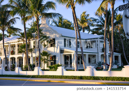 Colonial House Facade Along A Palm Lined Street With Holiday Wreaths 141533754