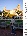 Woman Walking On A Brick Path Near A Historic Hotel At Dusk 141533780