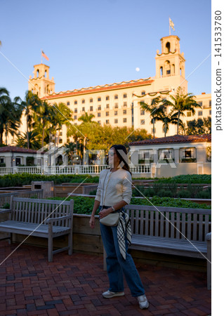 Woman Walking On A Brick Path Near A Historic Hotel At Dusk 141533780