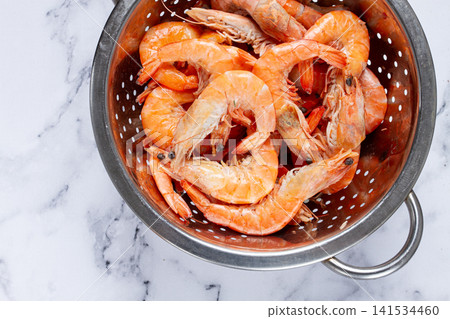 freshly frozen shrimp in a metal colander, for cooking, top view, close-up, on a marble table, no people, freshly frozen shrimp in a metal colander, for cooking, top view, close-up, on a marble table, no people, 141534460