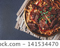Udon noodles with beef in Mongolian style, with green onions and vegetables, homemade, on a dark background, 141534470