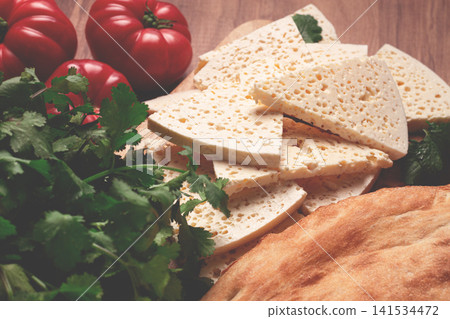 Georgian sliced cheese,on a wooden chopping board, with tomatoes with herbs and lavash, rustic style, Georgian cuisine, no people Georgian sliced cheese,on a wooden chopping board, with tomatoes with herbs and lavash, rustic style, Georgian cuisine, no people 141534472
