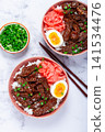 Gyudon Japanese beef with rice, pickled ginger, boiled egg slice, garnished with green onions, in a bowl with chopsticks, 141534476
