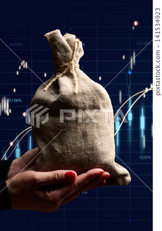 A woman's hands hold a tied canvas bag of money against a blurred digital stock market chart A woman's hands hold a tied canvas bag of money against a blurred digital stock market chart 141534923