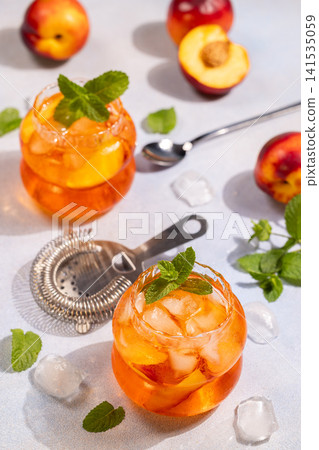 Refreshing iced peach tea cocktails with mint garnish Refreshing iced peach tea cocktails with mint garnish 141535059