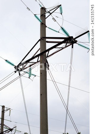 High-voltage power lines. Top of a concrete power line pole with rusty metal cross bars and glass pin insulators. 141535745