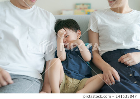 一個男孩和他的父母一起坐在沙發上。 一個男孩和他的父母一起坐在沙發上。 141535847