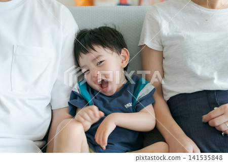A boy sitting on a sofa with his parents. A boy sitting on a sofa with his parents. 141535848