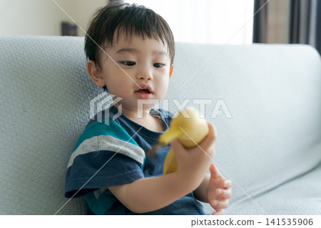 一個笑容燦爛的男孩手裡拿著一根香蕉 一個笑容燦爛的男孩手裡拿著一根香蕉 141535906