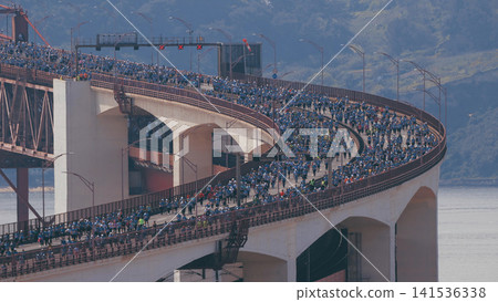 Running Lisbon half marathon crossing the 25 of April bridge over the Tagus river aerial view from above. 141536338