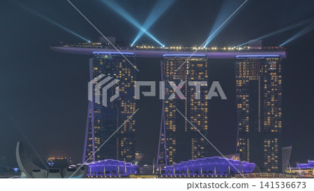 Fifty-five storeys high Marina Bay Sands Hotel dominates the skyline at Marina Bay in Singapore aerial night timelapse. Fifty-five storeys high Marina Bay Sands Hotel dominates the skyline at Marina Bay in Singapore aerial night timelapse. 141536673