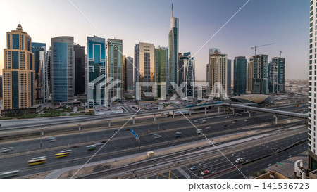 Aerial view of Jumeirah lakes towers skyscrapers night to day timelapse with traffic on sheikh zayed road. Aerial view of Jumeirah lakes towers skyscrapers night to day timelapse with traffic on sheikh zayed road. 141536723