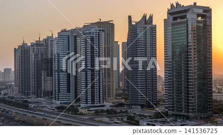 Aerial view of Jumeirah lakes towers skyscrapers night to day timelapse with traffic on sheikh zayed road. 141536725