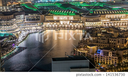 Night aerial view Dancing fountains downtown and in a man-made lake timelapse in Dubai, UAE. Night aerial view Dancing fountains downtown and in a man-made lake timelapse in Dubai, UAE. 141536730