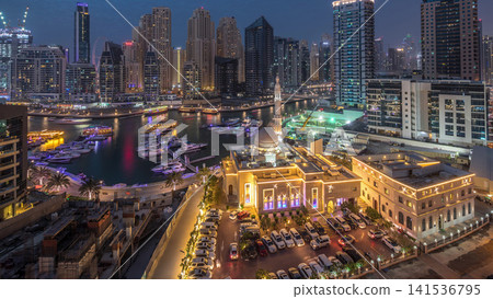 Yachts in Dubai Marina flanked by the Al Rahim Mosque and residential towers and skyscrapers aerial day to night timelapse. Yachts in Dubai Marina flanked by the Al Rahim Mosque and residential towers and skyscrapers aerial day to night timelapse. 141536795