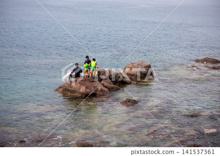 A family enjoying playing in the tide pools at Kotogahama Beach in Manazuru Town during the summer. A family enjoying playing in the tide pools at Kotogahama Beach in Manazuru Town during the summer. 141537361