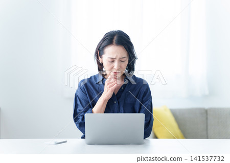 一位表情憂慮的中年婦女正在辦公桌前工作。 一位表情憂慮的中年婦女正在辦公桌前工作。 141537732