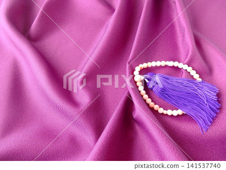 Prayer beads on a purple cloth drape Prayer beads on a purple cloth drape 141537740