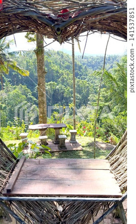 Heart shaped bamboo structure framing a viewing platform with a rustic wooden table and stone stools, providing a serene tropical jungle panorama in a popular tourist destination Heart shaped bamboo structure framing a viewing platform with a rustic wooden table and stone stools, providing a serene tropical jungle panorama in a popular tourist destination 141537851