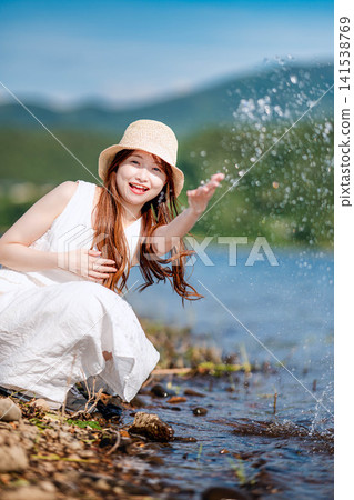 一名女子在湖邊玩耍,水花四濺。 一名女子在湖邊玩耍,水花四濺。 141538769
