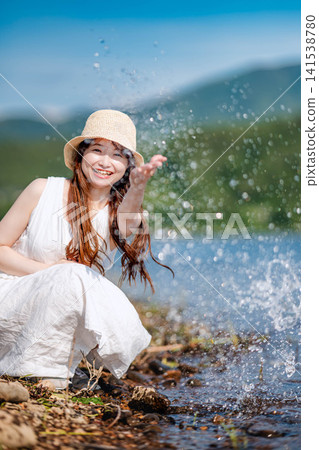 一位戴著草帽的女子在湖邊嬉戲玩耍。 一位戴著草帽的女子在湖邊嬉戲玩耍。 141538780