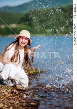 一名女子在水邊戲水玩耍。 一名女子在水邊戲水玩耍。 141538821