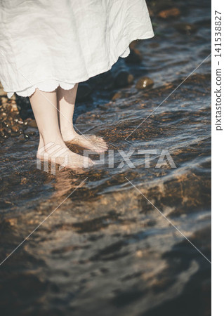 A woman's bare feet dipping in the lake. A woman's bare feet dipping in the lake. 141538827