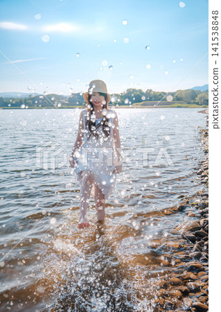 一名戴著草帽的女子踢了踢水面，濺起水花。 141538848