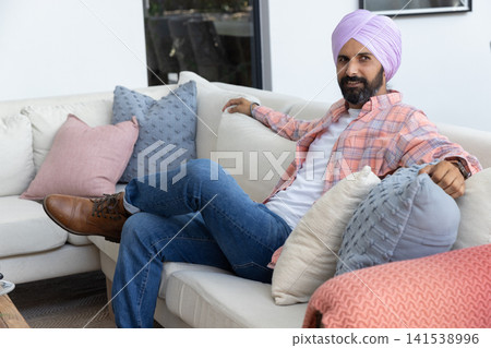 Indian man leaning sofa at home, wearing turban, wristwatch, copy space Indian man leaning sofa at home, wearing turban, wristwatch, copy space 141538996