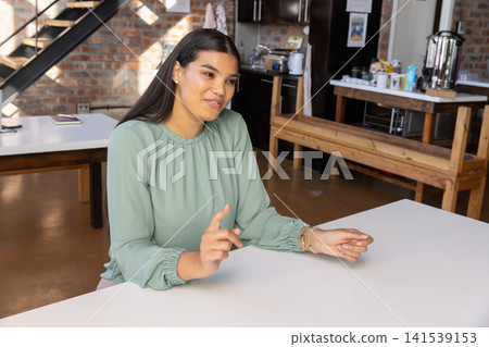 Woman sitting at white rectangular table in office with closed laptop on side table Woman sitting at white rectangular table in office with closed laptop on side table 141539153