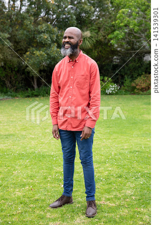 African american senior male standing in garden smiling in red shirt, blue jeans and boots African american senior male standing in garden smiling in red shirt, blue jeans and boots 141539301