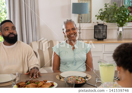 African American family sharing dinner at home around table with salad platter and lemonade pitcher African American family sharing dinner at home around table with salad platter and lemonade pitcher 141539746