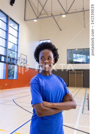 African american female in sportswear standing on gym basketball court with hoop African american female in sportswear standing on gym basketball court with hoop 141539839