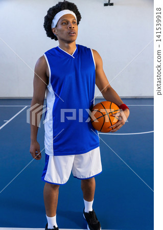 African american male basketball player standing on court in blue jersey holding basketball 141539918