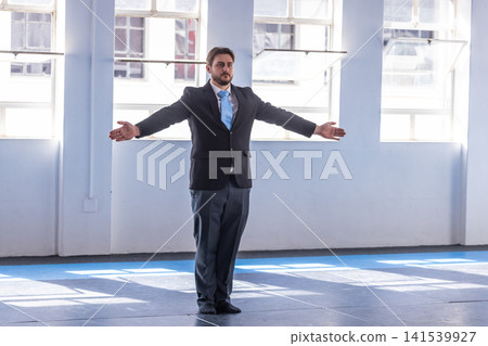 Man wearing suit holding arms extended in martial studio with interlocking mats, copy space Man wearing suit holding arms extended in martial studio with interlocking mats, copy space 141539927