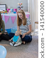 Mother and baby sitting on gray carpet at home baby shower, cupcake stand, letter board 141540000