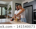 Couple placing raspberries container on kitchen island in home kitchen with mesh produce bag 141540073