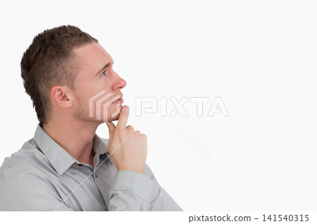 Man in twenties posing with hand on chin in studio wearing gray button-up shirt, copy space Man in twenties posing with hand on chin in studio wearing gray button-up shirt, copy space 141540315