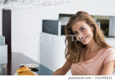 Woman sitting at glossy cafe counter smiling, wearing peach top croissants on plate, copy space Woman sitting at glossy cafe counter smiling, wearing peach top croissants on plate, copy space 141540411