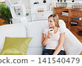 Woman aged 20s reclining on white sofa holding mug with shelving at home, copy space 141540479
